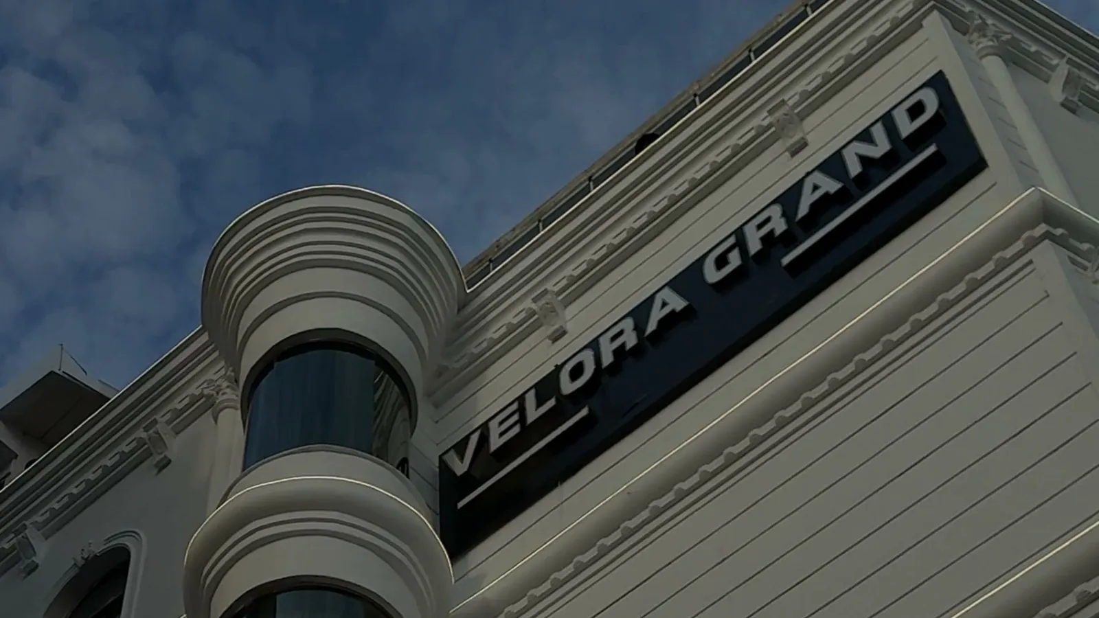 Upper part of the Velora Grand facade with the VELORA GRAND sign