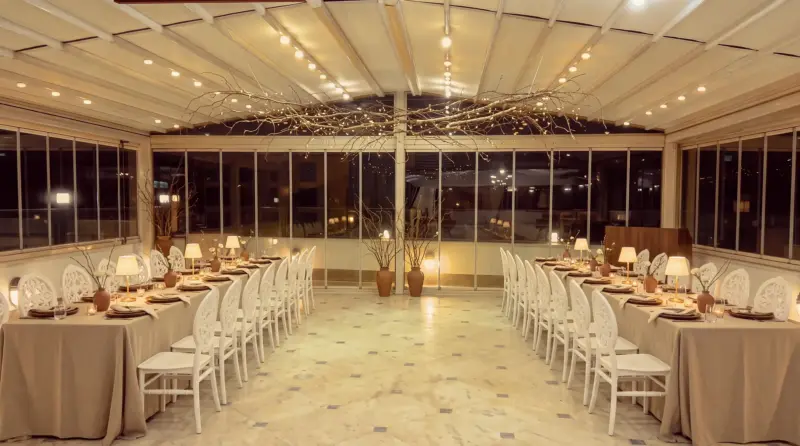 Walnut concept for an adult birthday: branch ceiling and side rows of tables across the terrace